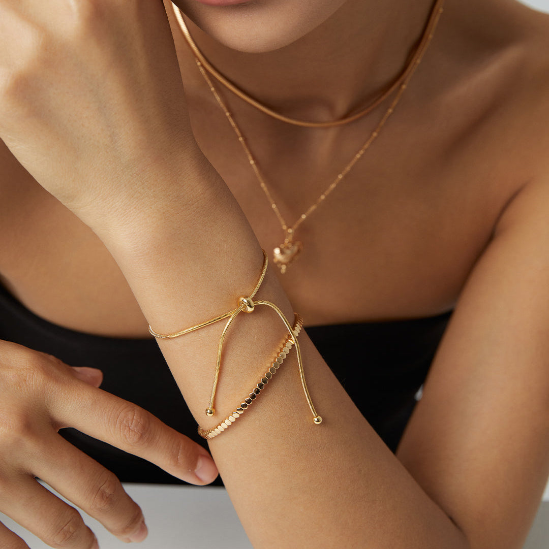 Modell trägt mehrere goldene Armbänder mit Schiebeverschluss im Layering-Look